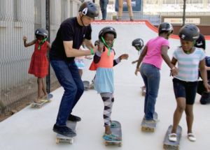 Tony Hawk teaching young Black skateboarders