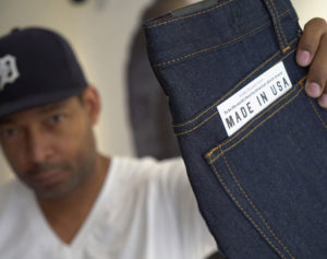 Denim designer Maurice Malone holding up Williamsburg Garment Co. made in USA raw selvedge jeans