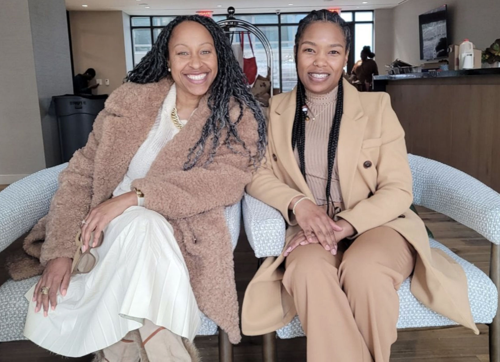 Afiya Ricks wearing long white dress and coat sitting next to her team partner.