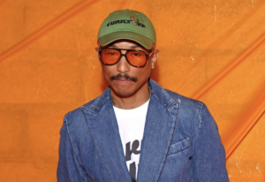 Pharrell Williams with a denim blazer and fashionable shades.